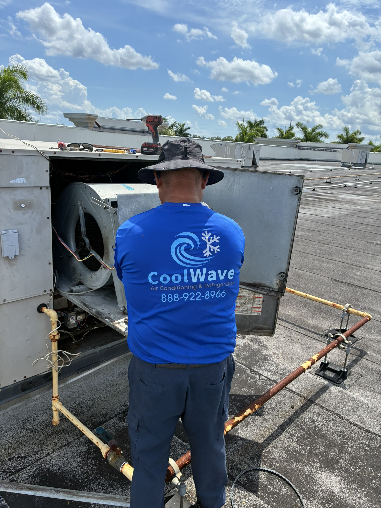 CoolWave technician performing AC repair work on a rooftop unit