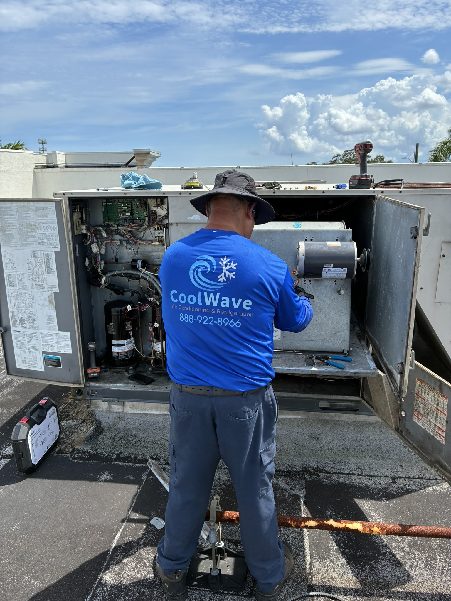 CoolWave technician servicing a commercial rooftop AC unit