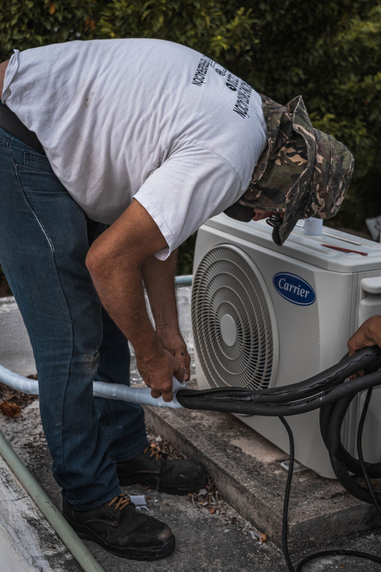 Technician performing maintenance on an outdoor AC unit