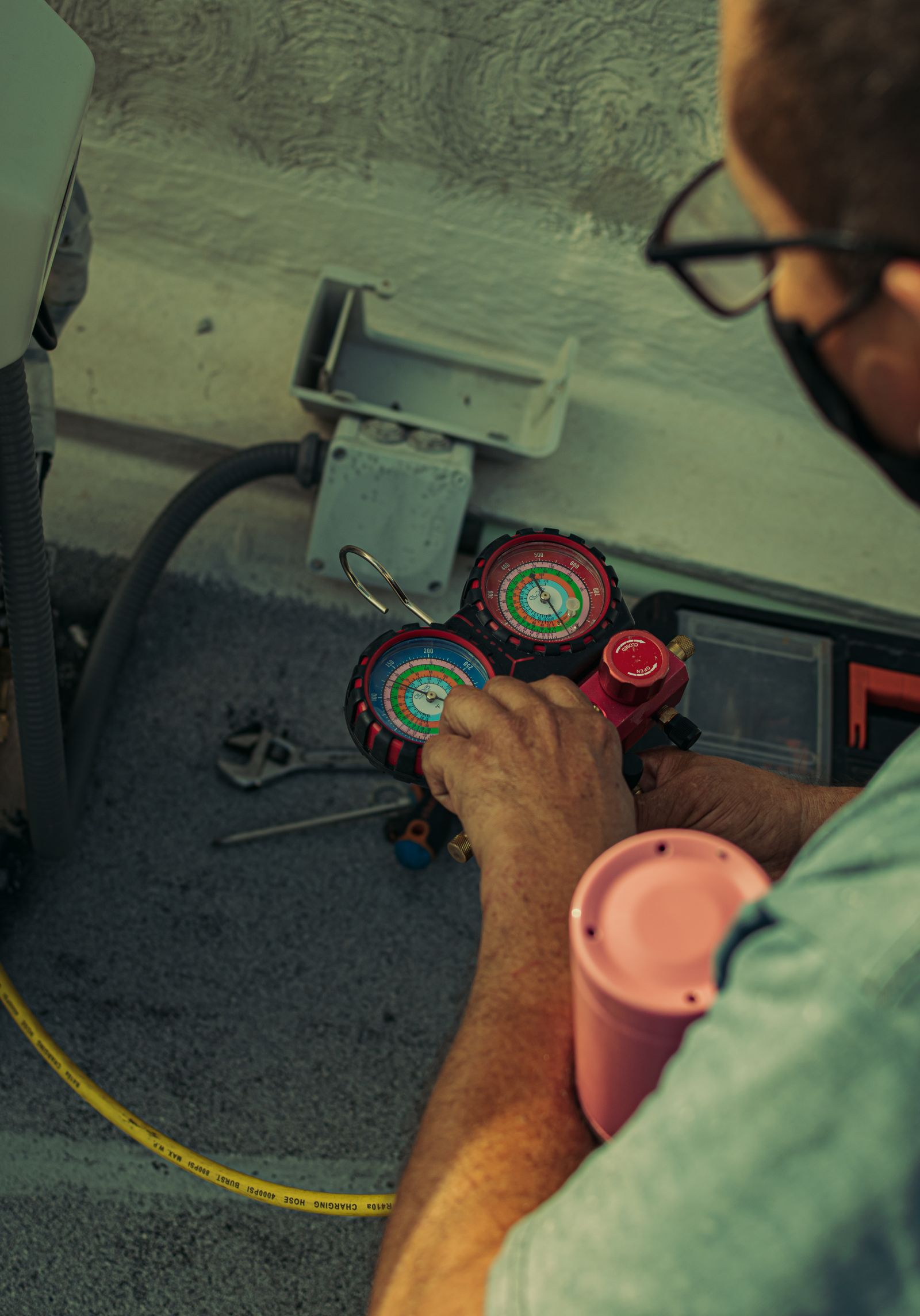Technician adjusting a refrigerant manifold gauge on an AC system
